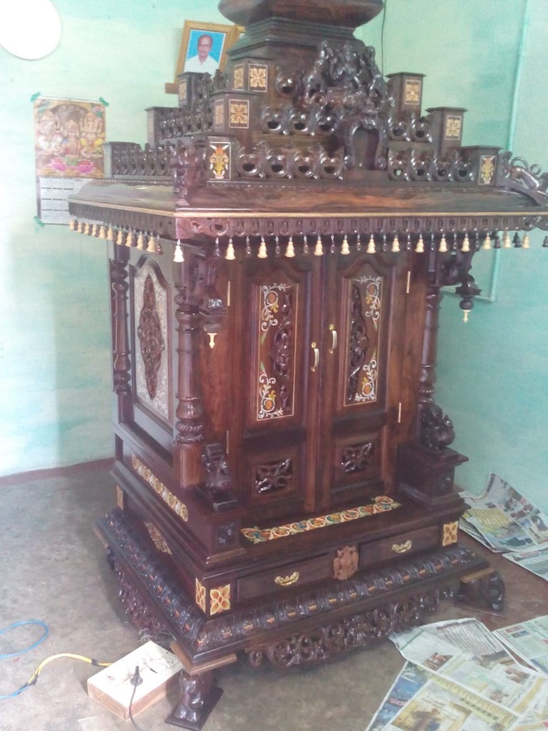 Three-quarter view of a large rosewood temple with a kalasha crown and hanging beads