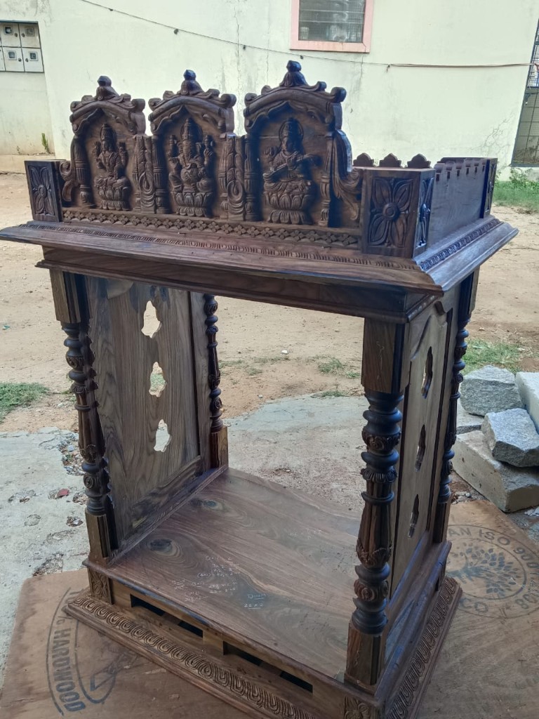 An unfinished carved frieze of three deities, outdoors at the workshop